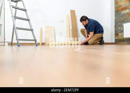 Young person doing DIY work at home. Photography at ground level. Natural day light. White wall. High quality photo. Stock Photo