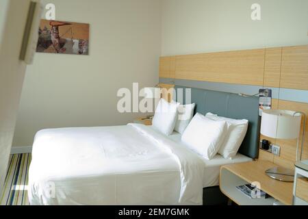 King-size bed in empty modern cozy attic hotel bedroom, brightly lit through the window Stock Photo