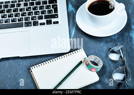 A cup of tea, laptop, notebook and glasses on blue desk Stock Photo