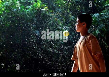 Cumilla, Bangladesh - November 24, 2017: The boy is splashing water with a cricket ball Stock Photo