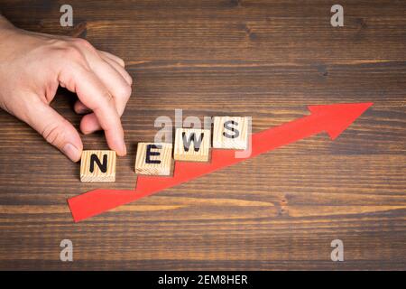 NEWS. Red arrow indicates the development and growth. Steps, wooden background. Stock Photo