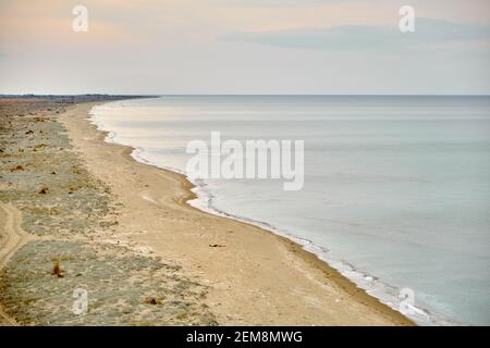 Beach, shore of marmara sea in Mudanya and shore and huge sand empty beach during winter with overcast weather during sunset. Stock Photo
