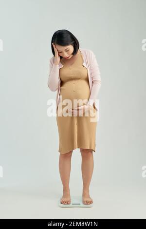 Pregnant woman standing on scales at home. Pregnancy weight gain concept Stock Photo