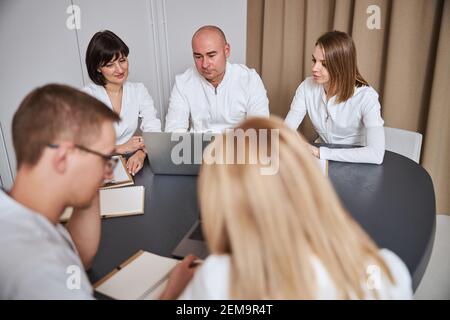 Bald chief doctor sitting with his colleagues at the table Stock Photo
