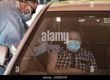 Santiago, Chile. 24th Feb, 2021. An elderly woman receives a dose of COVID-19 vaccine at a drive-through vaccination center in Parque O'Higgins in downtown Santiago, Chile, Feb. 24, 2021. Chile expects to have 80 percent of its population vaccinated against the novel coronavirus disease (COVID-19) by midyear, achieving so-called 'herd immunity,' Health Minister Enrique Paris said Wednesday.Health officials estimate the bulk of the target population, about 15 million Chileans, could be inoculated by June, Paris told local media. Credit: Jorge Villegas/Xinhua/Alamy Live News Stock Photo