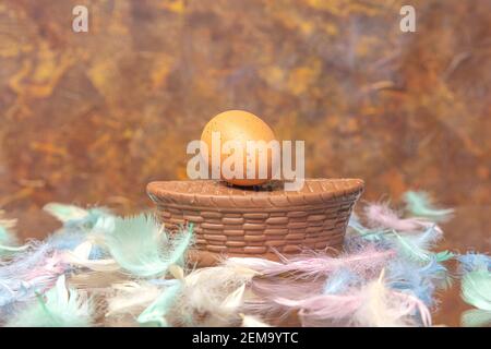 Chocolate basket and egg, multi-colored feathers on a brown background. Concept, Easter, congratulation, levitation, There is a place for text. High quality photo Stock Photo