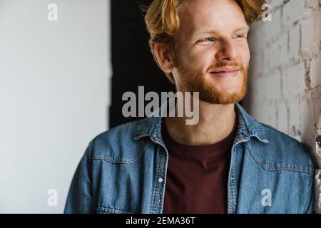 Happy handsome ginger guy smiling and looking aside indoors Stock Photo