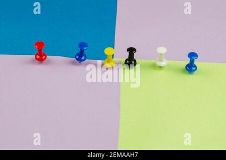 Push pins and lots of colorful sticky notes. Red, blue, yellow, black, white pushpins on a multicolored background. Side view at an angle. Selective f Stock Photo