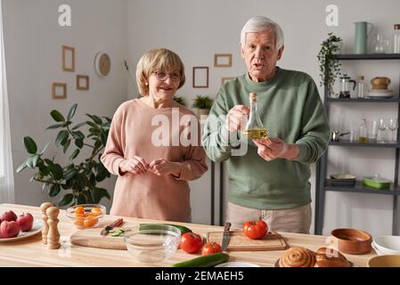 Senior couple standing at the kitchen table with food and preparing food together Stock Photo