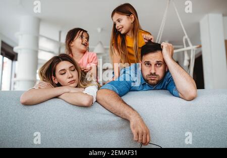 Tired mother and father feels annoyed exhausted while noisy little kids at home Stock Photo
