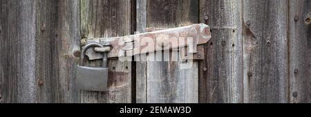 Panorama close  up view of old rusty clasp and padlock on wooden door Stock Photo