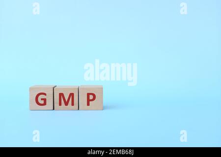 GMP word text on wooden blocks in blue background with copy space. Good manufacturing practice. Stock Photo
