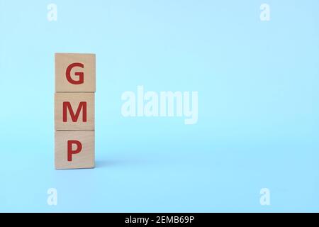 GMP word text on wooden blocks in blue background with copy space. Good manufacturing practice. Stock Photo