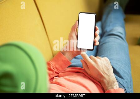 Smartphone blank screen. A man on the couch uses a smartphone at home. Online shopping and delivery concept. Stock Photo
