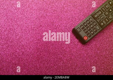 Tv remote in on a pink glitter glamor background. Cinema, entertainment, TV concept. Stock Photo