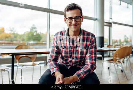 Portrait of a positive businessman sitting in office. Happy young businessman smiling at camera. Stock Photo