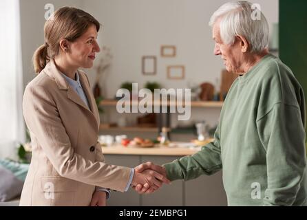 Young businesswoman shaking hands with senior man after their successful meeting Stock Photo