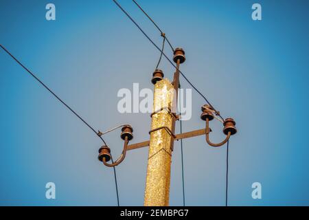 Top of an old electrical pole with plugs and wires on a blue sky background. Stock Photo