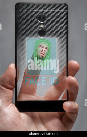 the concept of Face ID . the face on the finger touches the sensor biometrics on the phone screen. Stock Photo