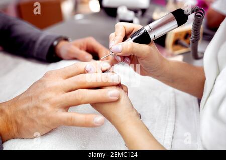 Manicurist using electric nail file on the nails of her customer, neat nails Stock Photo