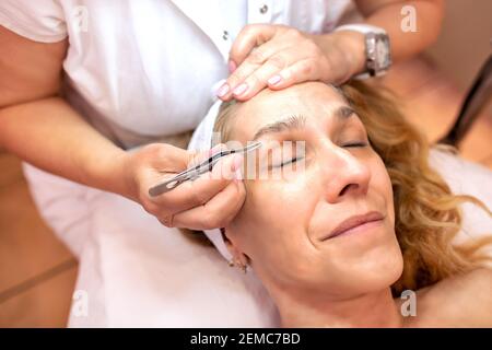Middle aged woman getting an eyebrow treatment in a beauty salon Stock Photo