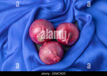 Whole purple fresh onions on blue tablecloth Stock Photo