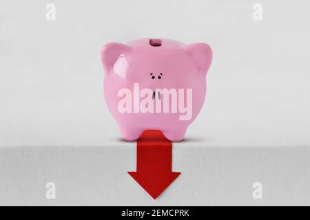 Piggy bank with red down arrow - Financial crisis and loss of money concept Stock Photo