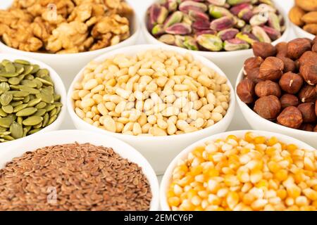 The various kind of nuts and seeds in the white ceramic bowls. Stock Photo