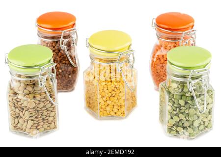 The collection of different groats in the glass jars isolated on white background. Split peas, buckwheat and colorful lentils. Stock Photo