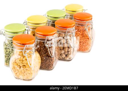 The collection of different groats in the glass jars isolated on white background. Buckwheat, chickpea, pea and lentils. Stock Photo