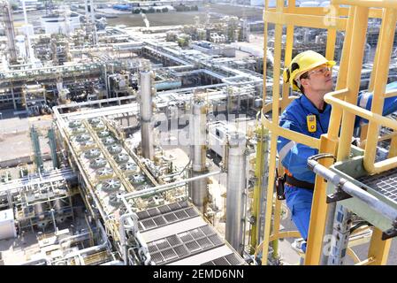 chemical industry plant - workers in work clothes in a refinery with pipes and machinery Stock Photo