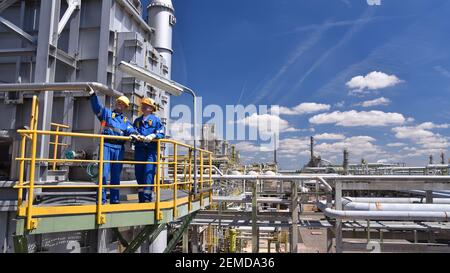 teamwork: group of industrial workers in a refinery - oil processing equipment and machinery Stock Photo