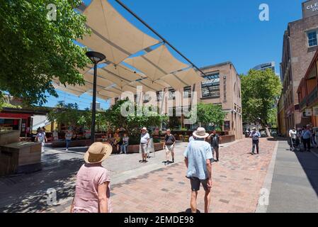 Shade sails mounted above an open courtyard provide tourists and shoppers with welcome shade on a hot summer's day in The Rocks, Sydney, Australia Stock Photo