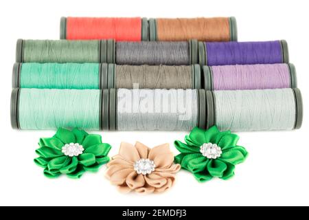 Colorful cotton thread reels and fabric flowers isolated on white background. Stock Photo