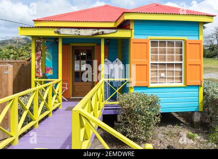 Colourfully painted wooden shack raised off the ground open as a shop on the island of Nevis in the Caribbean in bright sunlight, no people Stock Photo