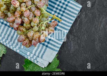 A bunch of red grapes with leaves and blue tablecloth on dark background Stock Photo