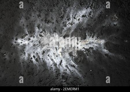 Artistic, abstract high contrast image: bright oil spill on dark concrete form like infection, cancer or pollution spreading; color photo. Stock Photo