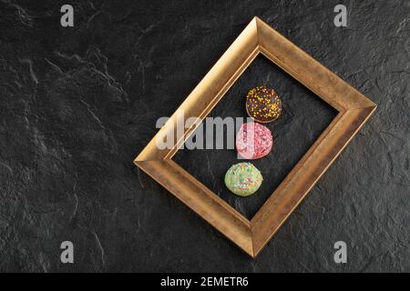 Sweet small doughnuts with sprinkles on a black background Stock Photo