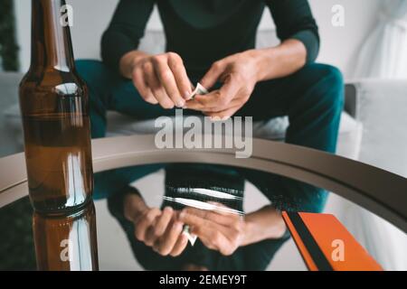 Junkie drinking beer and ready to sniff cocaine. Narcotics and alcohol addiction Stock Photo