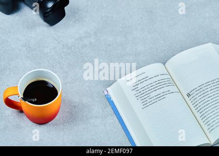 Open book, camera and coffee cup on gray table Stock Photo