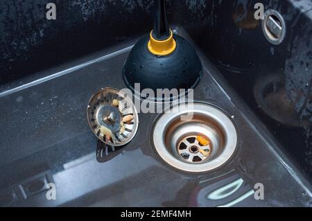 Plunger and clogged kitchen sink. Pipe cleaning concept. Sanitary engineering work. Stock Photo
