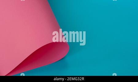 Blue background with rolled pink paper sheet. Minimal concept Stock Photo