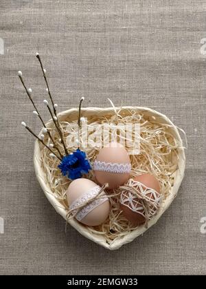 Easter composition decorated by lace Easter eggs in wicker basket on linen background Stock Photo
