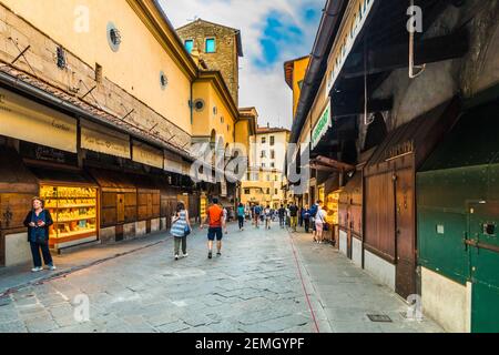 Italian jewelry shops on the bridge Ponte Vecchio in Florence. People are crossing the bridge and taking a stroll to admire the shops under the... Stock Photo