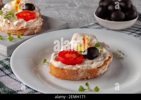 Fresh homemade crispy bread toast with tomato, poached egg and olive. A quick snack made from good food Stock Photo