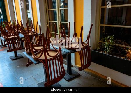 Stacked chairs on the table due to covid-19 pandemic precautions. Closed restaurant background photo. Stock Photo