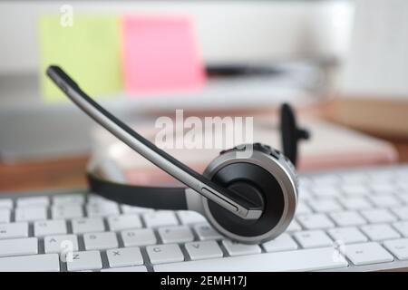 Black headset lying on computer keyboard closeup Stock Photo