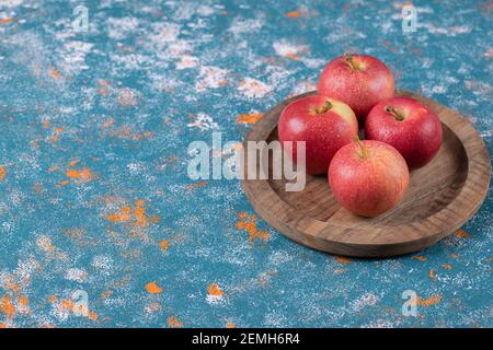 Juicy apples in a wooden platter on the blue background Stock Photo
