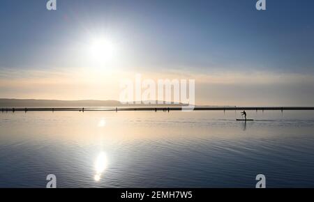 A paddle boarder paddles along West Kirby Marine Lake during the sunset on the 22nd of February 2021 Stock Photo