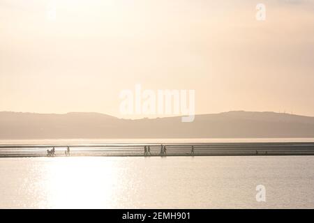 People walk along the Marine lake footpath in West Kirby, Wirral, England. Stock Photo